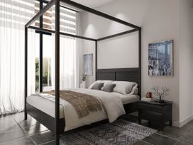 A bedroom with a canopy bed and nightstand at Kew Villa (Pet) in Marhamchurch