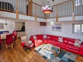 A living room with a red sofa and dining area at Calf House Spa in Marhamchurch
