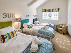 A bedroom with three beds and a chair at Calf House Spa in Marhamchurch
