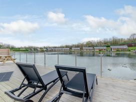 An outdoor area with deck chairs and a table near a body of water at Tranquillity 4 in Carnforth