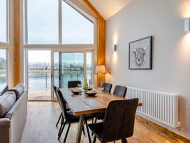 A dining room with a table and chairs near large windows at Tranquillity 4 in Carnforth