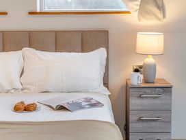 A bedroom with a bed, pillows, croissants, a magazine, and a lamp at Tranquillity 4 (Pet) Carnforth