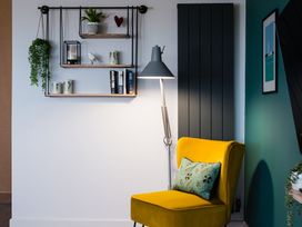 A living room with a yellow chair and wall shelf at The Irvine in North Berwick