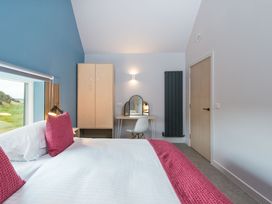 A bedroom with a bed, wardrobe, desk, and mirror at The Irvine in North Berwick