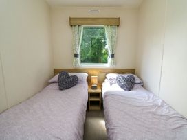 A bedroom with two single beds and a window at Caravan 6 at Blackmoor Farm near tenby