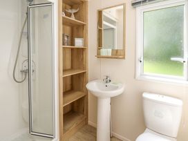 A bathroom with a shower unit and storage shelf at Caravan 6 at Blackmoor Farm near tenby Narberth