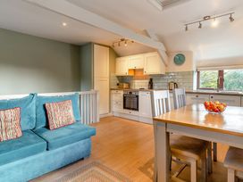 A living room and kitchen with a sofa and dining table at Crabtree Cottage in Bude
