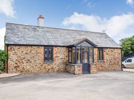 The exterior of a stone cottage with a parking area at Godolphin Stable Bude