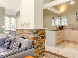 A living room with a sofa and kitchen area at Godolphin Stable Bude