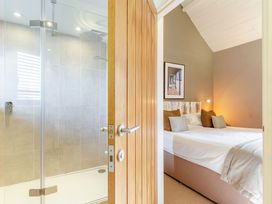 A bathroom with a shower and a bedroom with a bed at Godolphin Stable in Bude