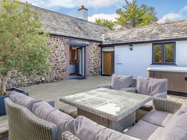 An outdoor area with seating and a hot tub at Godolphin Stable, Bude
