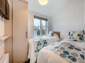 A bedroom with two single beds and a wardrobe at Kynance Spa (Pet) Bude