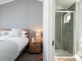 A bedroom with a bed and adjacent shower at Kynance Spa (Pet) Bude