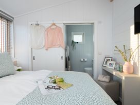 A bedroom with hanging clothes and an attached bathroom at Mullion 2 Spa in Bude
