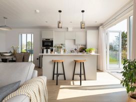 A kitchen with bar stools and a sliding door at Sennen 2 Spa Roof Terrace (Pet) Bude