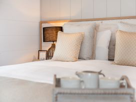 A bedroom featuring a bed with pillows and a bedside lamp at Sennen 2 Spa Roof Terrace (Pet) Bude
