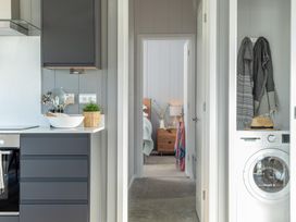 A kitchen with cabinets, sink, stove and a washing machine at Kynance (Pet) in Bude