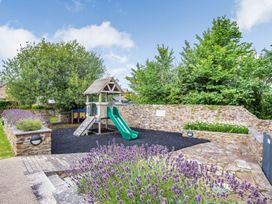 An outdoor playground with a slide and playhouse at Kynance (Pet) Bude
