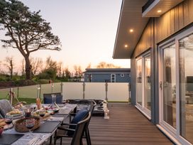 A dining setup with table and chairs on a deck at Mullion 2 Spa (Pet) Bude