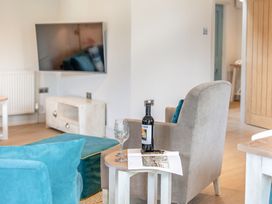 A living room with a chair and table at Summerleaze Garden Cottage 3 Spa in Bude