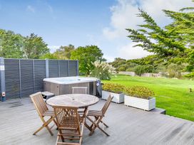 An outdoor area with a hot tub and a wooden table at Summerleaze Garden Cottage 3 Spa Bude