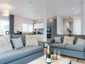 A living room with sofas and a kitchen in the background at The Glasshouse in Bude