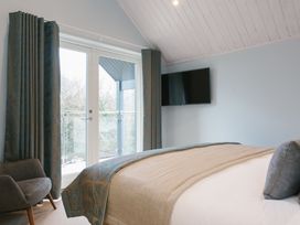 A bedroom with a bed, curtains, and a television at The Glasshouse in Bude