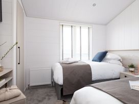 A bedroom with two beds and a bedside table at Sennen 3 Spa Roof Terrace (Pet) Bude