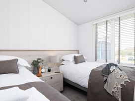 A bedroom with two beds and a bedside table at Sennen 3 Spa Roof Terrace (Pet) in Bude