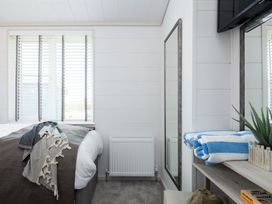 A bedroom with a bed and a mirror at Sennen 3 Spa Roof Terrace (Pet) Bude