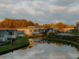 A view of holiday homes by a pond at Sennen 3 Spa Roof Terrace in Bude