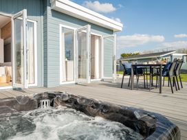 An outdoor area with a hot tub and dining table at Sennen 3 Spa (Pet) in Bude