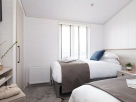 A bedroom with two beds and a nightstand at Sennen 3 Spa (Pet) Bude