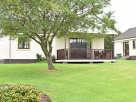 A house with a deck and tree in the outdoor area at Arran Lodge Spa in Dailly