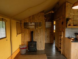 A tent interior with a wood stove and kitchen area at Standard Safari Tent Fair Oak