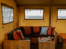 A living room with a sofa, table, and game board at Standard Safari Tent in Fair Oak