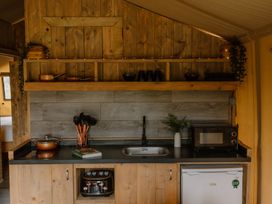 A kitchen with a sink, microwave, and storage at Deluxe Safari Tent in Fair Oak