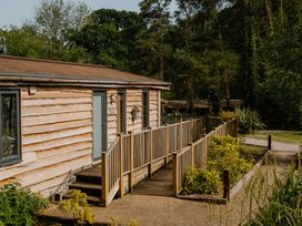 A cabin with a wooden deck and pathway at Spitfire Lodge in Fair Oak