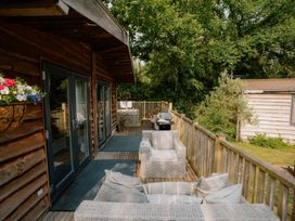 An outdoor deck with chairs and a grill at Spitfire Lodge in Fair Oak