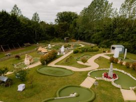 An outdoor mini golf course with trees and benches at Spitfire Lodge in Fair Oak