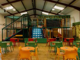 An indoor play area with a climbing frame and slide at Spitfire Lodge in Fair Oak