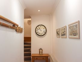 A hallway with a clock and coat hooks at The Little Clock House in Dartmouth