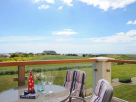 A terrace with a table and chairs overlooking a field at 8 Thurlestone Beach in Kingsbridge