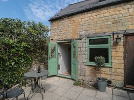 An outdoor area with a green door and table at Wheelwright Cottage in Moreton-In-Marsh