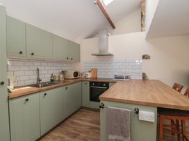 A kitchen with green cabinets and wooden countertop at Wheelwright Cottage in Moreton-In-Marsh