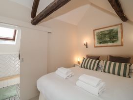 A bedroom with a bed and decorative pillows at Wheelwright Cottage in Moreton-In-Marsh