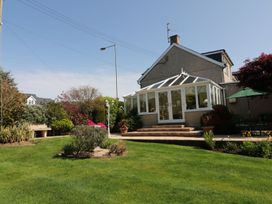 A garden with a conservatory and patio area at Llwyn Derw in Talybont