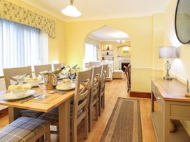 A dining room with a table set for meals and a living area at Llwyn Derw Talybont