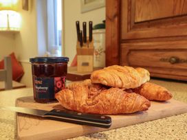 A kitchen with croissants and jam on a cutting board at Llwyn Derw Talybont