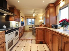 A kitchen with wooden cabinets and a dining table at Llwyn Derw in Talybont